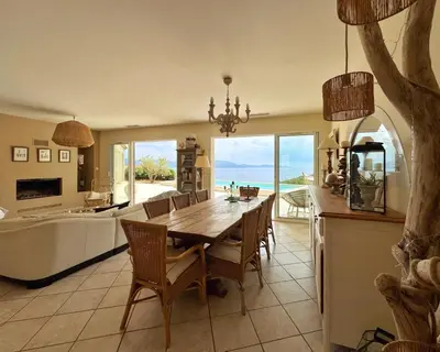 a dining room with a table and a view of the ocean at Villa Casa Bianca Sagone Piscine privée et Vue mer Familiale in Sagone