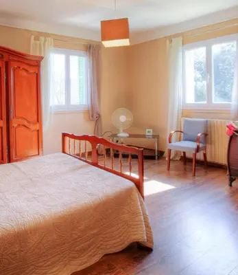a bedroom with a bed and a chair and windows at Casa santoni 20 in Grosseto-Prugna