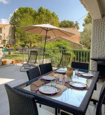 a table with chairs and an umbrella on a patio at Casa santoni 20 in Grosseto-Prugna