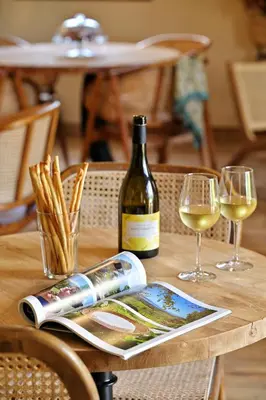 a bottle of wine and a magazine on a table with wine glasses at COCO in Venaco