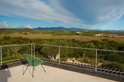 a green chair on a balcony with a view of a field at Villa esprit moderniste avec piscine in Bonifacio