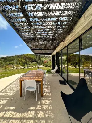 a table and chairs on a patio with a roof at Villa esprit moderniste avec piscine in Bonifacio