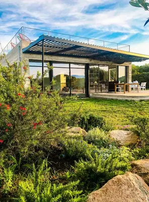 a house with a roof over a garden with rocks at Villa esprit moderniste avec piscine in Bonifacio