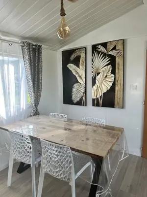 a dining room table with chairs and paintings on the wall at les bungalows de Lisa Maria in SERRA DI FIUMORBO