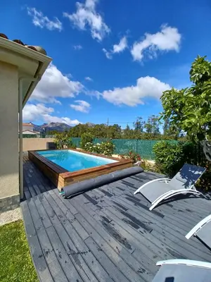 a backyard with a swimming pool and a wooden deck at maison cosy climatisée avec piscine et jardin in Calenzana