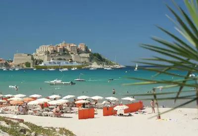 a beach with umbrellas and people on the beach at maison cosy climatisée avec piscine et jardin in Calenzana