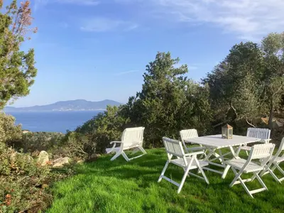 a picnic table and two chairs on the grass with the ocean at Domaine de la Coletta Bergerie in Coti-Chiavari