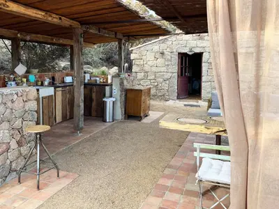 an outdoor kitchen and dining area of a stone building at Domaine de la Coletta Bergerie in Coti-Chiavari