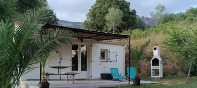 a small white house with two chairs and a table at Charmante maisonnette situé au calme proche d'Ajaccio. in Afa