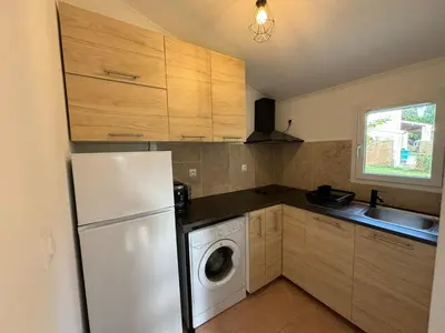 a kitchen with a refrigerator and a washing machine at Charmante maisonnette situé au calme proche d'Ajaccio. in Afa