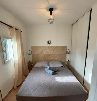 a bedroom with a bed with a blue pillow on it at Charmante maisonnette situé au calme proche d'Ajaccio. in Afa
