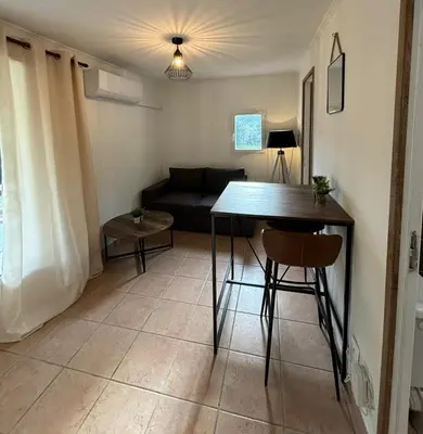 a living room with a table and a couch at Charmante maisonnette situé au calme proche d'Ajaccio. in Afa