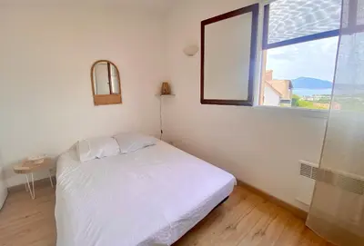 a small bedroom with a white bed and a window at Terra Bella - mini Villa vue mer in Grosseto-Prugna