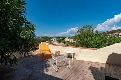 a patio with a table and chairs on a wooden deck at Terra Bella - mini Villa vue mer in Grosseto-Prugna