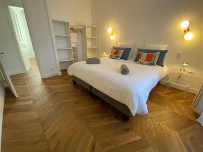 a large white bed in a room with wooden floors at Ajaccio : Appartement de grand standing vue mer. in Ajaccio