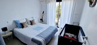 a bedroom with a bed with a suitcase next to a window at Villa Bistinetti Rez de villa tout confort avec piscine in Penta-di-Casinca