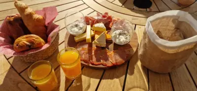 a wooden table with a plate of food and glasses of orange juice at Villa Bistinetti Rez de villa tout confort avec piscine in Penta-di-Casinca