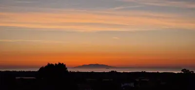 a sunset over the ocean with a mountain in the distance at Villa Bistinetti Rez de villa tout confort avec piscine in Penta-di-Casinca