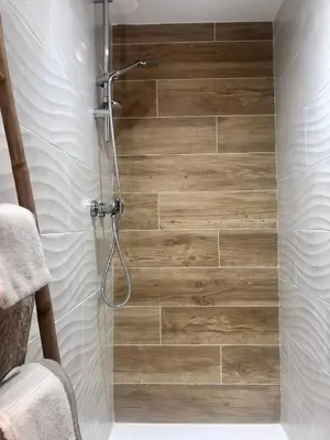 a bathroom with a shower with a wooden wall at U Vechju Fragnu in Vezzani