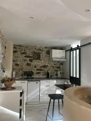 a kitchen with white cabinets and a stone wall at U Vechju Fragnu in Vezzani