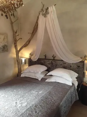 a bedroom with a bed with a canopy and white pillows at Villa St Exupery in Oletta