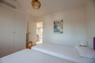 a white bedroom with two beds and a painting on the wall at DI SOGNI - Villa d'Archi, 8 pax, pisc Chauffée in Gialla