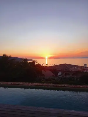a sunset over the ocean from a resort at Magnifique villa vue mer avec piscine in Coti-Chiavari