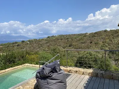 a chair sitting on a deck next to a swimming pool at Magnifique villa vue mer avec piscine in Coti-Chiavari