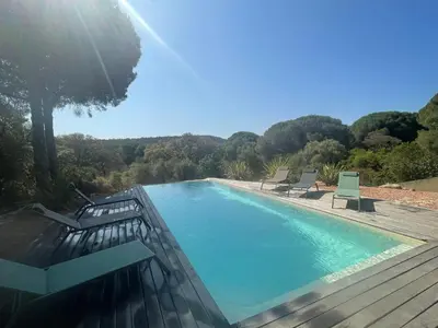 a swimming pool with two chairs on a wooden deck at Appartement spacieux à Porto-Vecchio avec piscine partagéeB in Porto-Vecchio