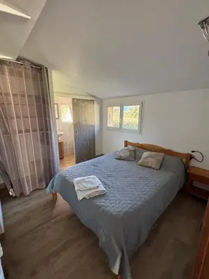a bedroom with a large bed and a bathroom at Rez de villa pour 2 personnes près de Santa Giulia in Sotta