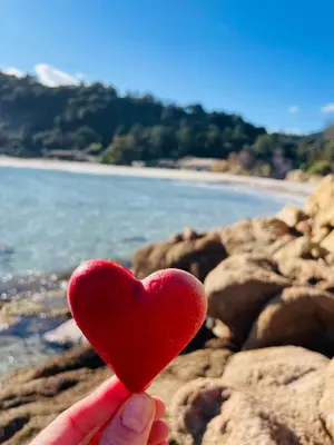 a person holding a red heart on a beach at Duplex vue mer EXCEPTIONNELLE en Corse du sud proche plage - le 180Corse in Conca