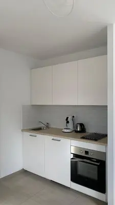 a kitchen with white cabinets and a black oven at Résidence Casa Olea - Studio - T2 - T3 in Cauro