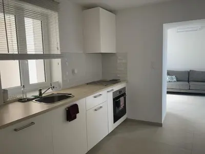 a kitchen with white cabinets and a sink and a couch at Résidence Casa Olea - Studio - T2 - T3 in Cauro