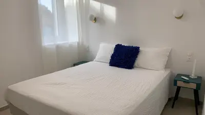 a white bed with a blue pillow on top of it at Résidence Casa Olea - Studio - T2 - T3 in Cauro
