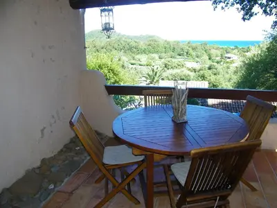 a wooden table and chairs on a balcony at Mini Villa St-Lucie Porto-Vecchio vue mer 5mnplage in Zonza