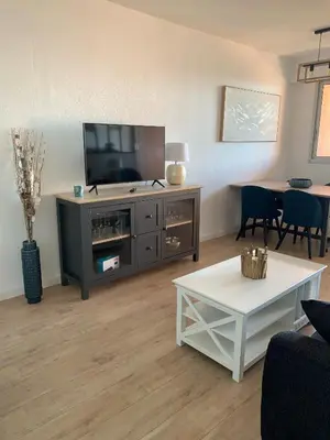 a living room with a television and a table at Appartement « Marinella » splendide vue mer aux Sanguinaires in Ajaccio
