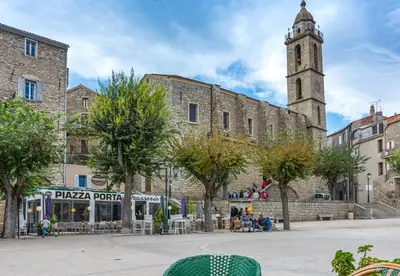 an old building with a clock tower in a city at SARTENE t3 CALME ENSOLEILLÉ PARKING PRIVÉ in Sartène