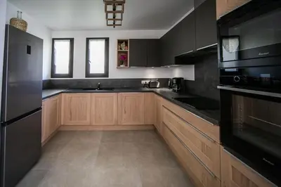a large kitchen with wooden cabinets and black appliances at SARTENE t3 CALME ENSOLEILLÉ PARKING PRIVÉ in Sartène