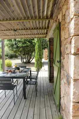 a patio with a table and chairs on a wooden deck at Maison 1 in Porto-Vecchio