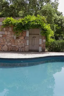 a door in a stone wall next to a swimming pool at Maison 1 in Porto-Vecchio