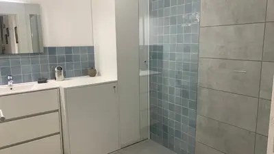 a bathroom with a sink and a shower with blue tiles at Duplex Horizon vue mer in Pietrosella