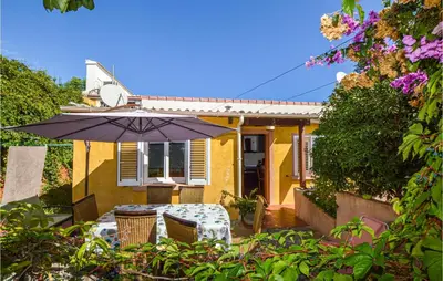 a patio with an umbrella and a table and chairs at 2 Bedroom Cozy Home In San Nicolao in San-Nicolao