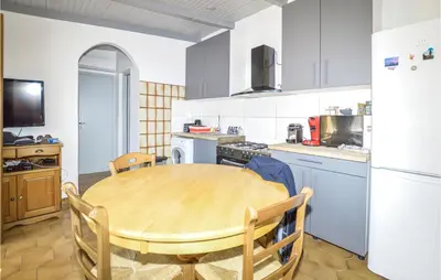 a kitchen with a wooden table and a kitchen with a refrigerator at 2 Bedroom Cozy Home In San Nicolao in San-Nicolao