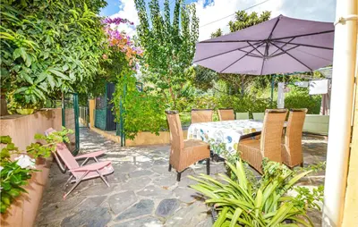 a patio with a table and chairs and an umbrella at 2 Bedroom Cozy Home In San Nicolao in San-Nicolao