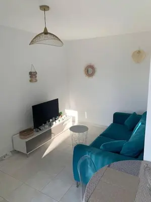 a living room with a blue couch and a tv at Appartement 35m2 climatisé a 10 min d’Ajaccio in Alata