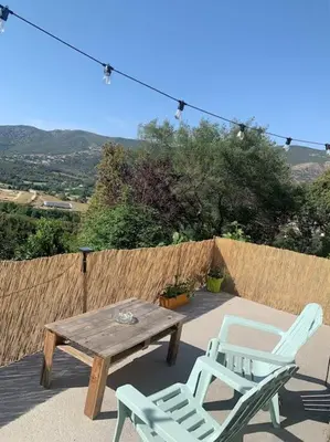 a wooden table and two chairs on a patio at Appartement 35m2 climatisé a 10 min d’Ajaccio in Alata