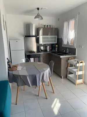 a kitchen with a table and a kitchen with a stove at Appartement 35m2 climatisé a 10 min d’Ajaccio in Alata