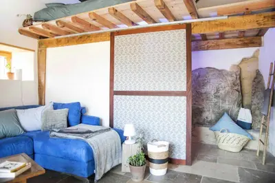 a living room with a blue couch and a bed at Eco lodge Carbonaccio in Chiatra
