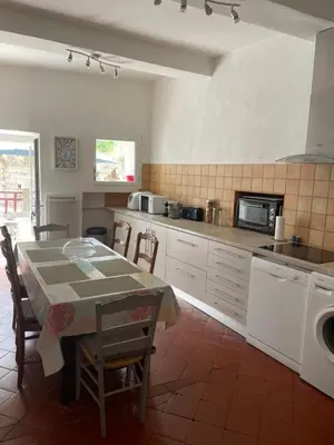a kitchen with a table and a washing machine at Maison de caractère rénovée Coggia in Coggia
