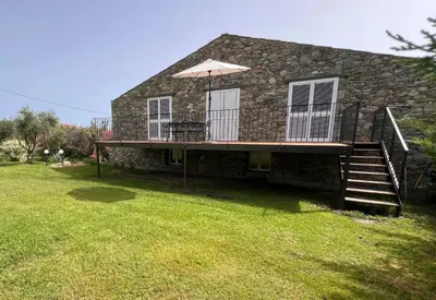 a house with a deck and an umbrella at Maison enchanteresse à Santo-Pietro-di-Tenda avec jacuzzi in Santo-Pietro-di-Tenda